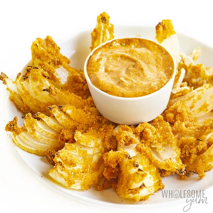 Cooked keto blooming onion on a plate and a bowl of dipping sauce
