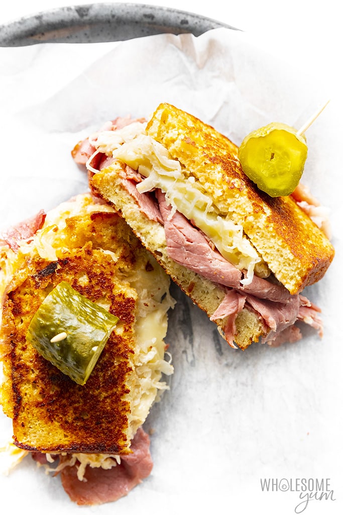 Keto reuben sandwich cut in half with pickles on top