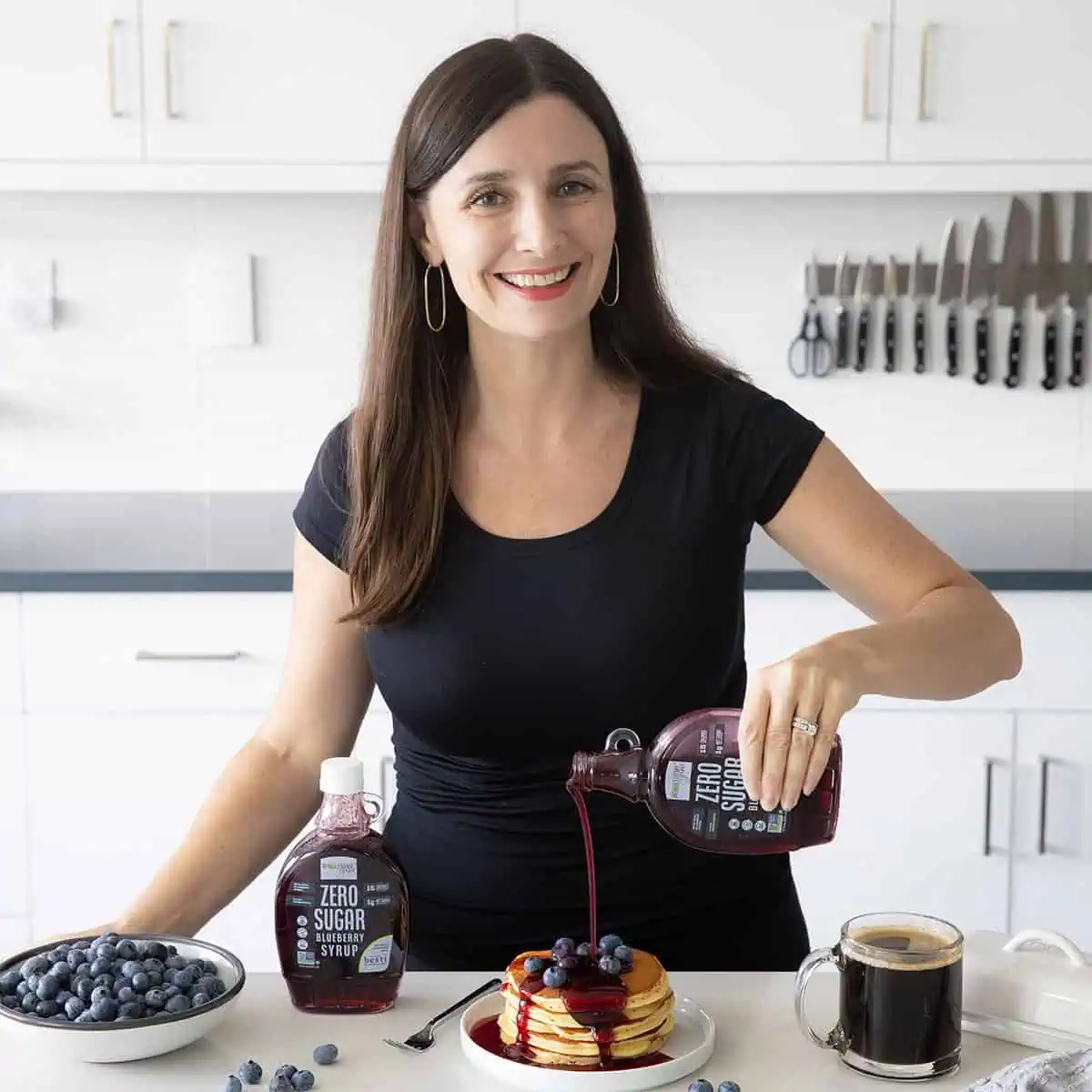 Maya Pouring Wholesome Yum Sugar Free Blueberry Syrup on Pancakes.